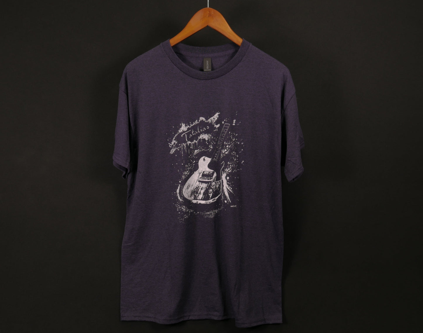 Purple t-shirt with a graphic design on a hanger against a black background