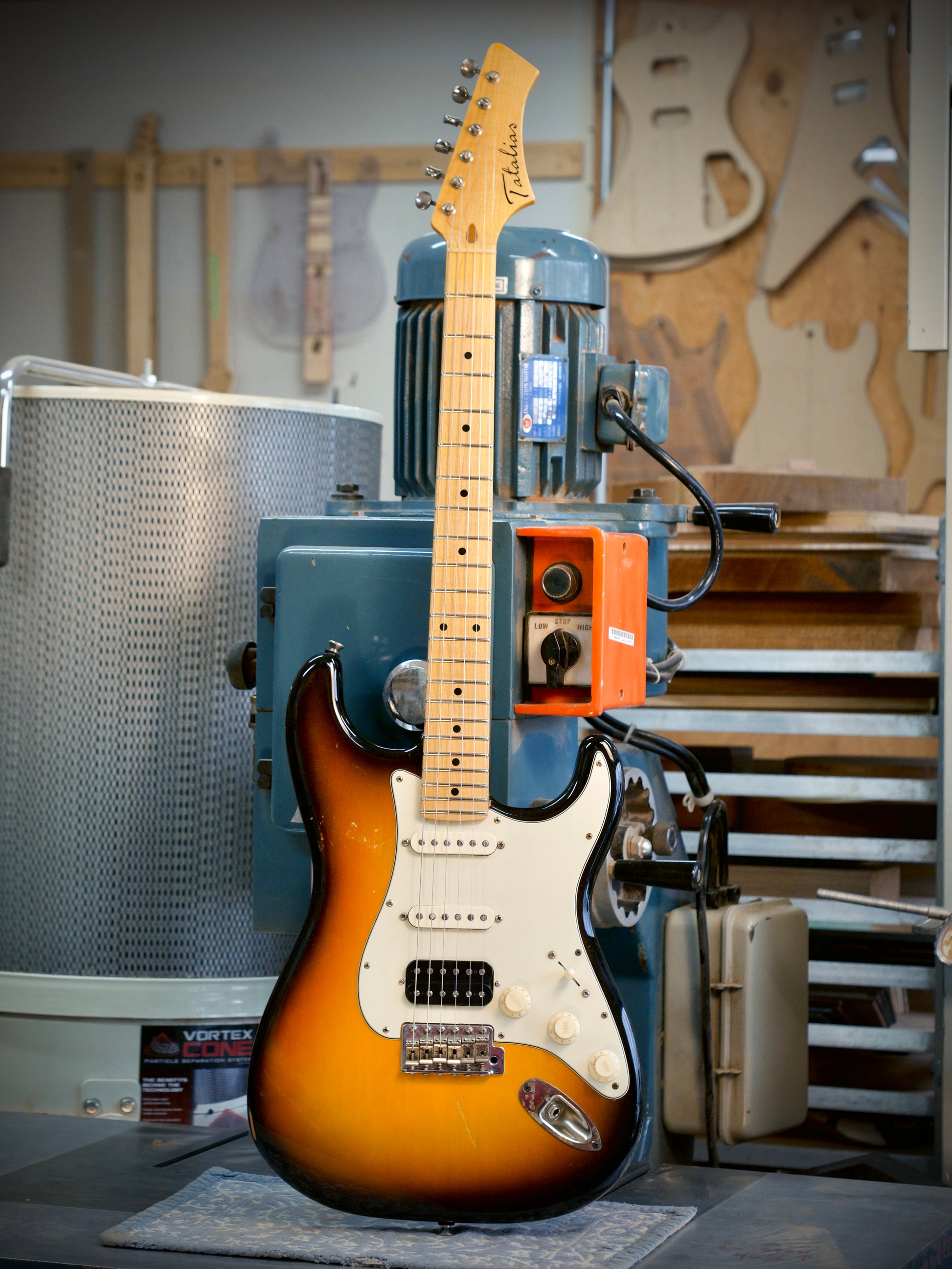 Electric guitar in a workshop setting with tools and equipment in the background